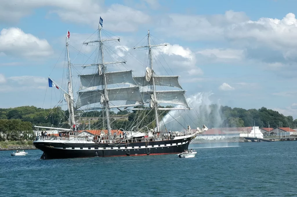 Le Belem en train de naviguer proche de la ville de Bayonne. Un jet d'eau sort du bateau.